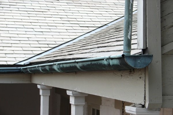 an old gutter system attached to a shingle roof